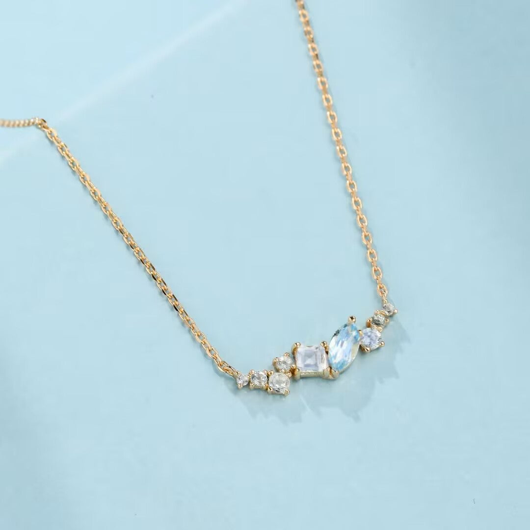 Collier ras du cou en argent 925 plaqué or 14K avec une cascade de pierres bleues et transparentes de formes variées, évoquant une couronne d'azur.