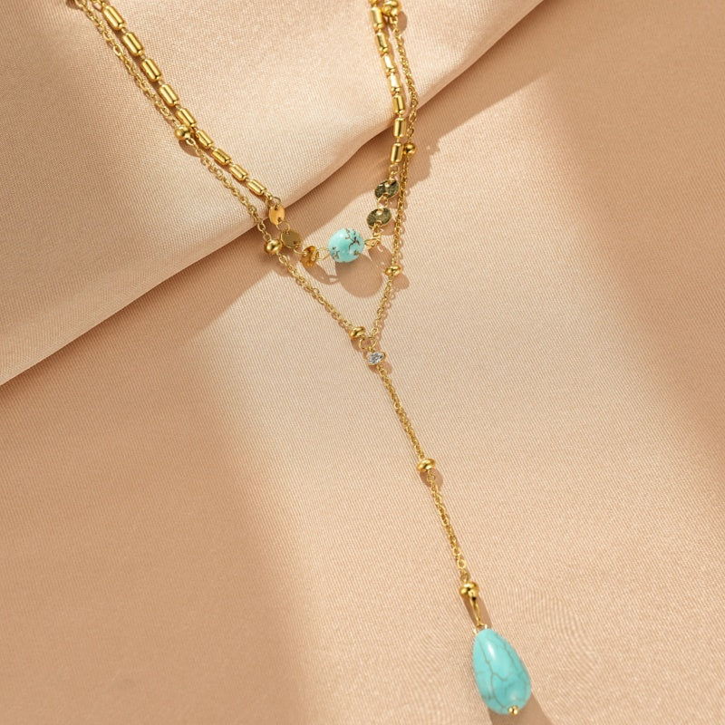 Collier plaqué or avec deux chaînes superposées, ornées de perles et de pierres turquoise naturelles en forme de goutte et de boule.
