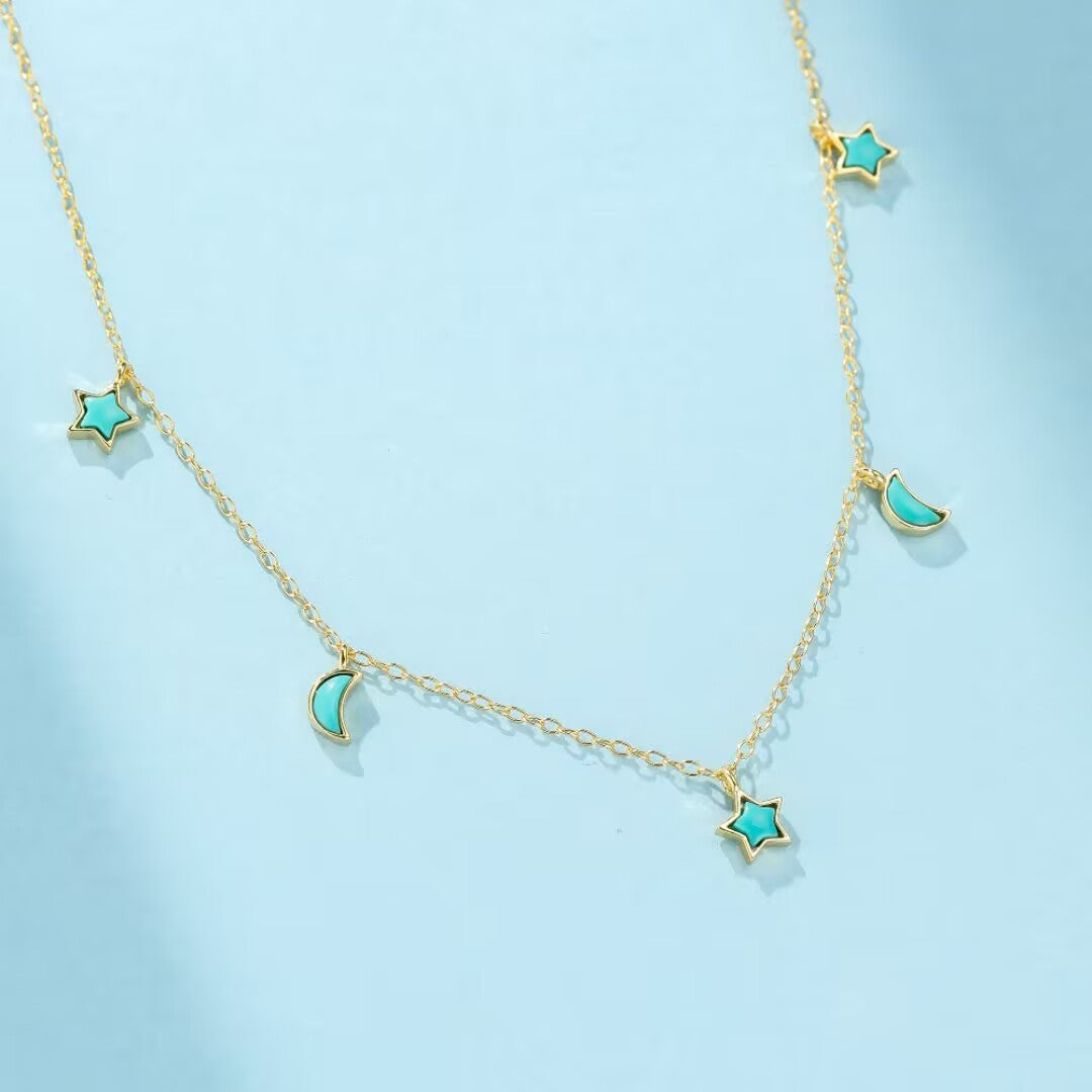 Collier plaqué or avec des breloques en turquoise en forme d'étoile et de lune sur une chaîne délicate.