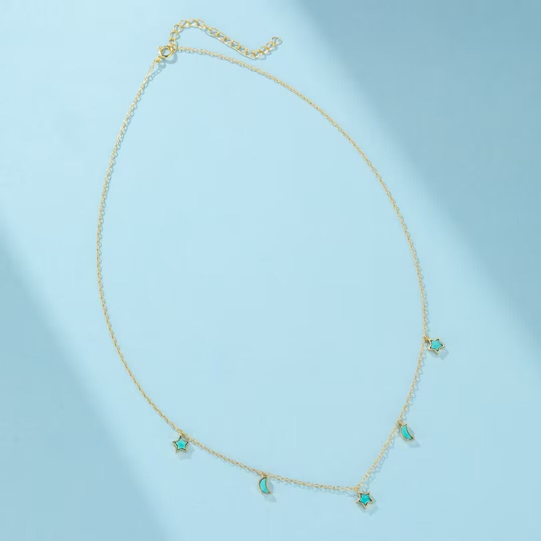 Collier plaqué or avec une chaîne fine ornée de petites étoiles et de croissants de lune bleus turquoise.