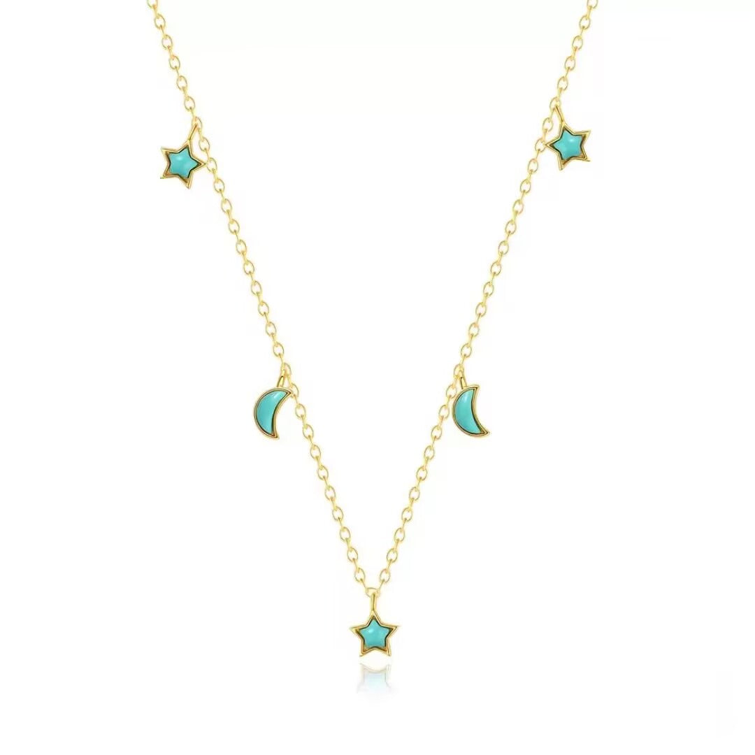 Collier plaqué or avec pendentifs en forme d'étoile et de lune incrustés de turquoise, sur fond blanc.