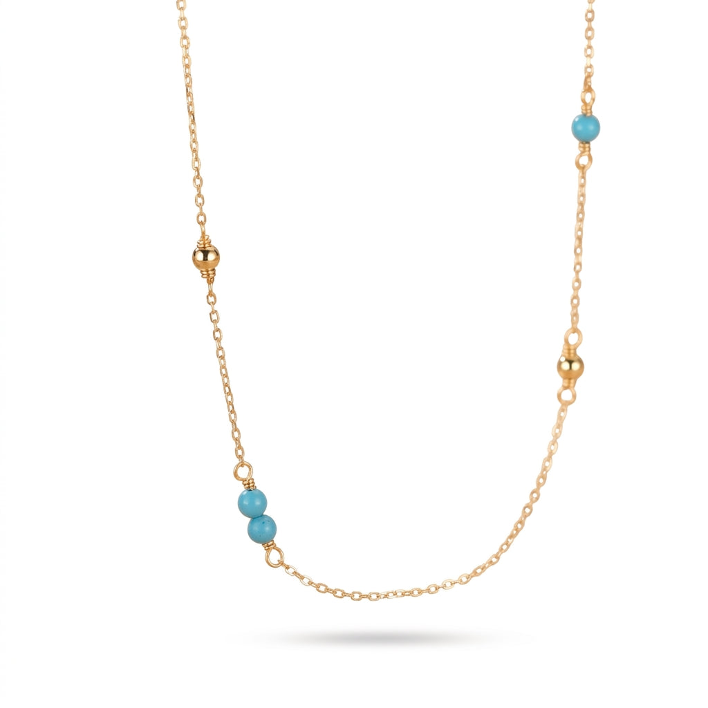 Collier chaîne plaqué or fin avec petites perles turquoise et détails dorés sur fond blanc