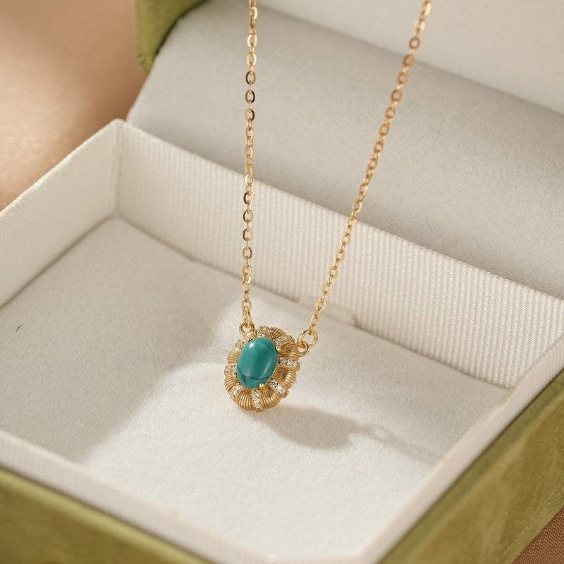 Collier en argent plaqué or avec une turquoise ovale et des zircons, présenté dans un écrin vert.