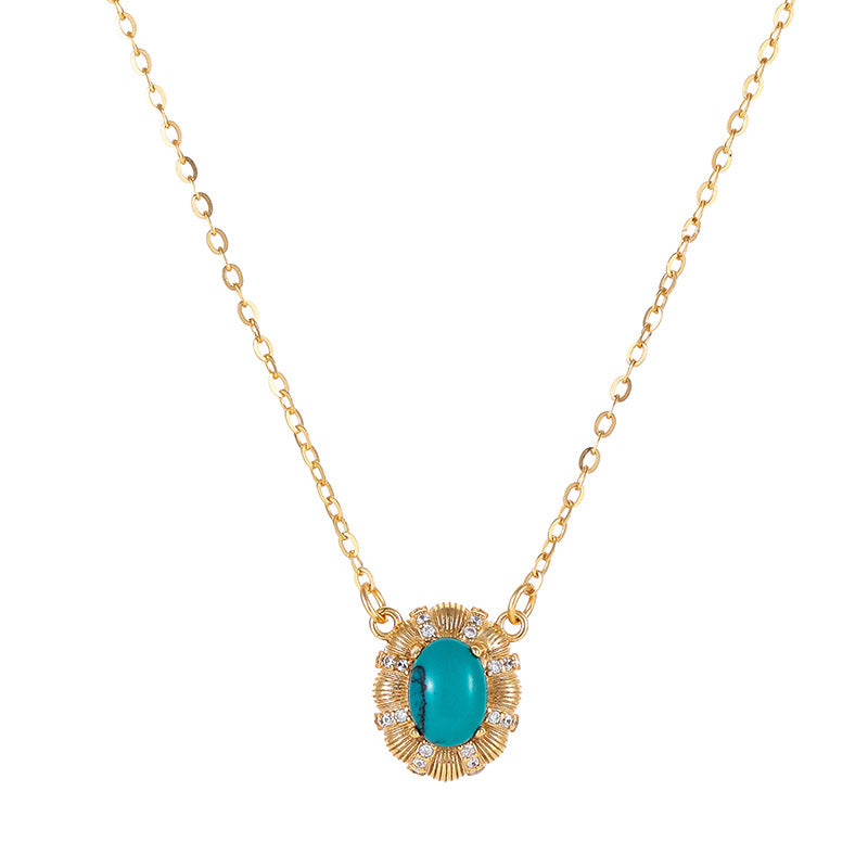 Collier en plaqué or avec une pierre turquoise ovale entourée de petites pierres scintillantes et une chaîne délicate.