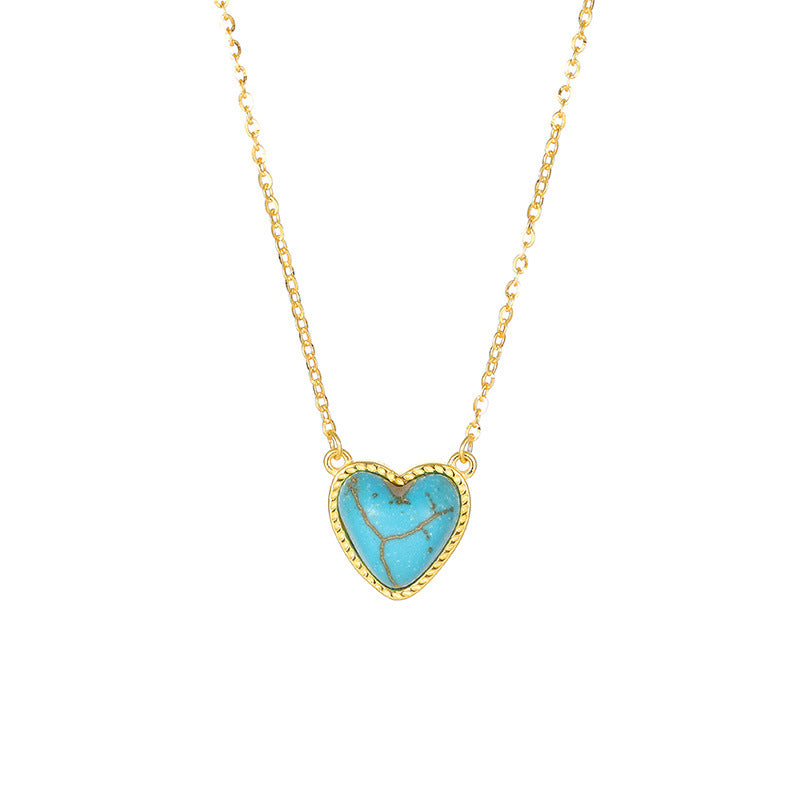 Collier en forme de cœur avec une turquoise bleue et des détails dorés, monté sur une chaîne plaquée or.