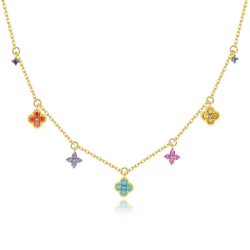 Collier plaqué or avec une chaîne fine ornée de plusieurs trèfles sertis de pierres multicolores: turquoise, rose, violet, orange, jaune et bleu.