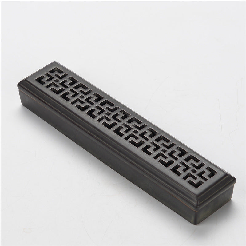 Encensoir rectangulaire en céramique noire avec motifs ajourés géométriques sur le dessus.