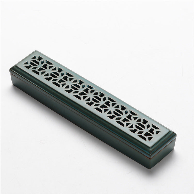Encensoir rectangulaire en céramique verte foncée avec un motif ajouré géométrique sur le dessus.
