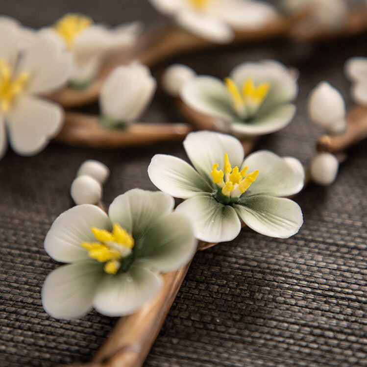 Encensoir Zen fait main en céramique avec des fleurs de cerisier blanches et jaunes délicates sur un fond de tissu sombre