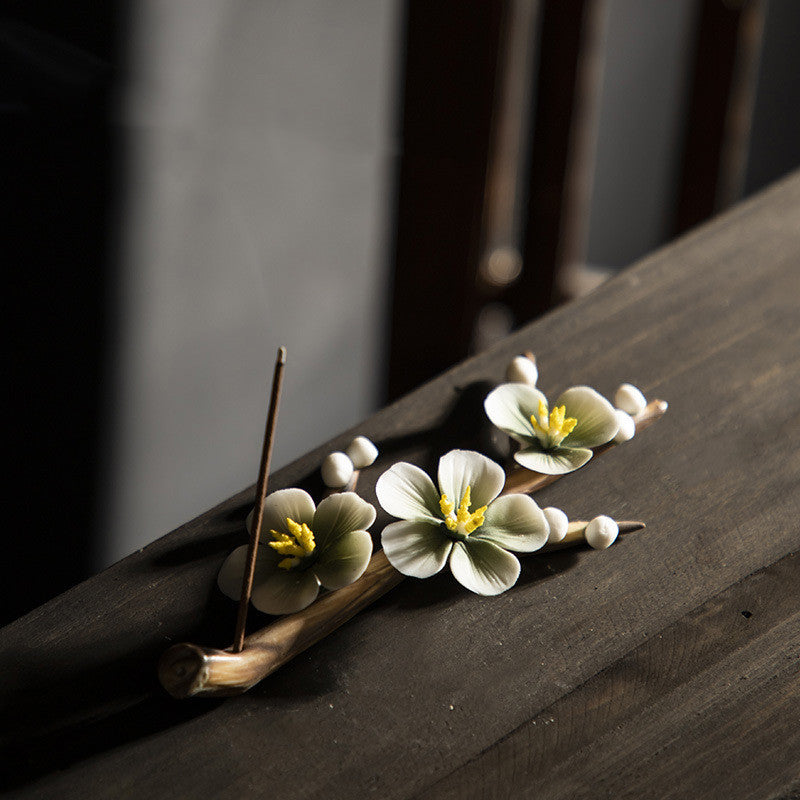 Encensoir zen en céramique fait main, décoré de fleurs de cerisier en porcelaine et de perles, avec un bâton d'encens allumé.