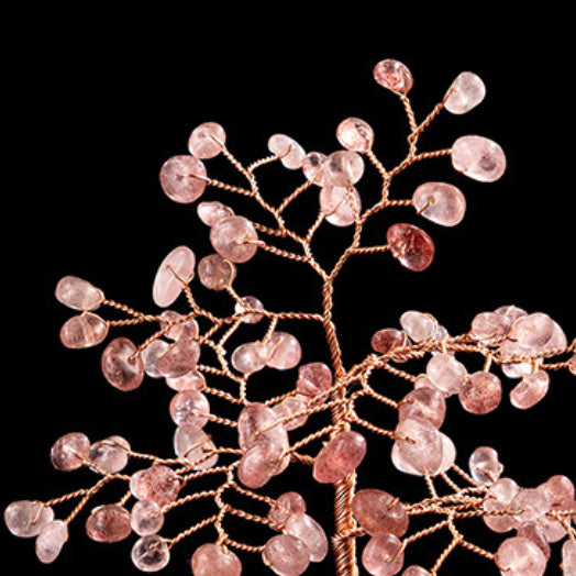 Gros plan d'un Arbre de Vie décoratif fait à la main, avec des branches en fil de cuivre rose et des feuilles en petites pierres de quartz fraise et d'agate translucides de couleur rose clair.