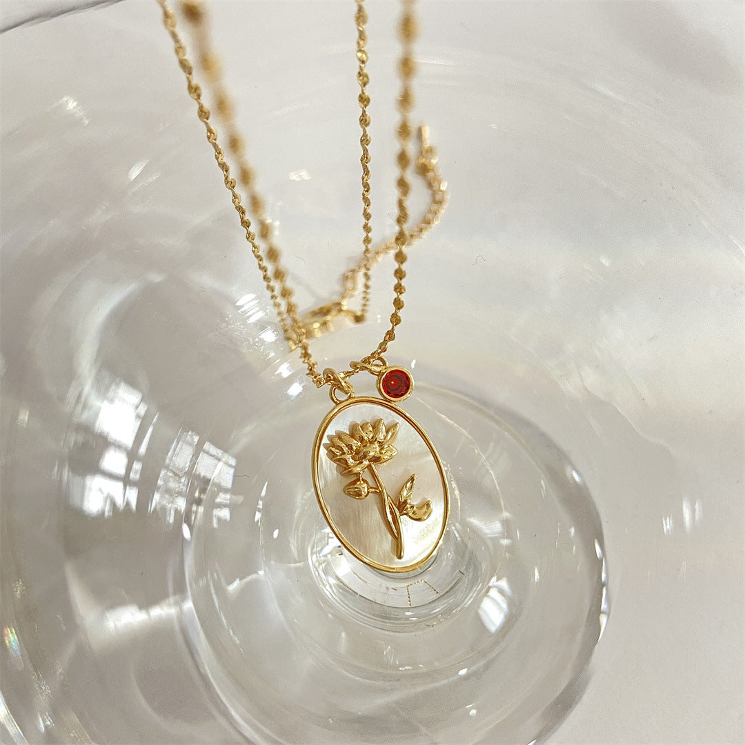 Pendentif Romance en or 12 pierres de naissance, avec une fleur de renoncule sculptée sur nacre et une petite pierre rouge.