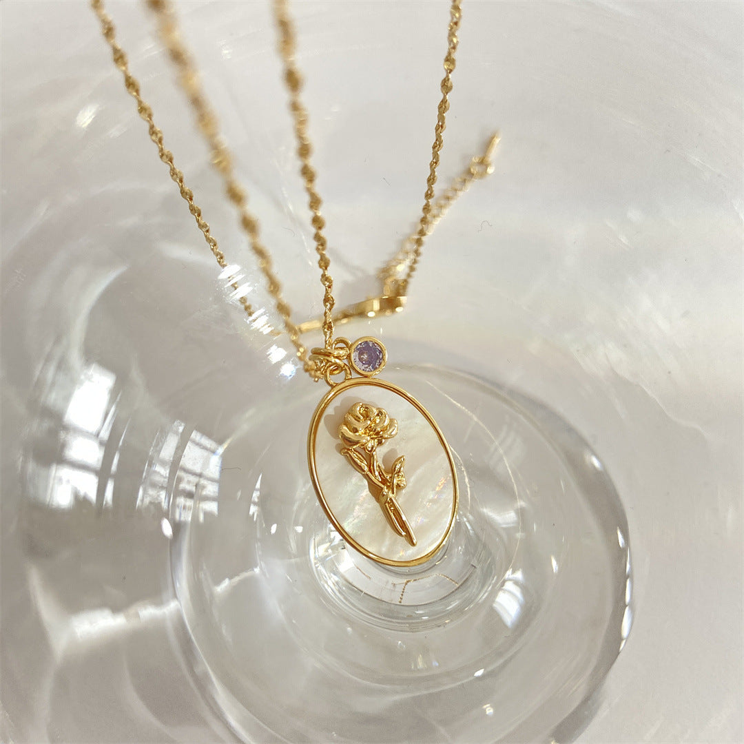 Pendentif 12 Pierres de Naissance Romance, avec un motif de rose dorée sur fond nacré et une petite pierre violette incrustée sur la chaîne.
