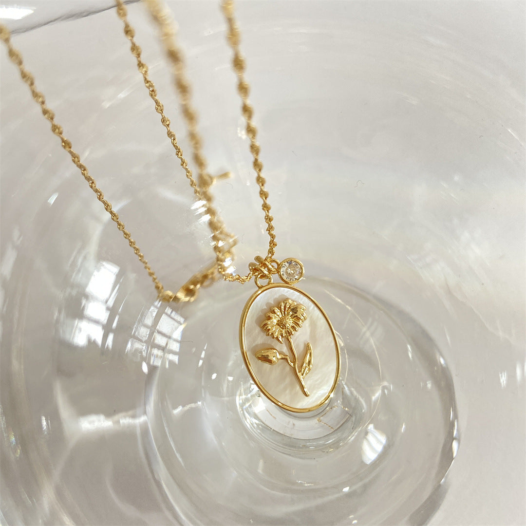 Pendentif en or avec une marguerite dorée sur fond nacré, faisant partie de la collection 12 Pierres de Naissance – Romance.