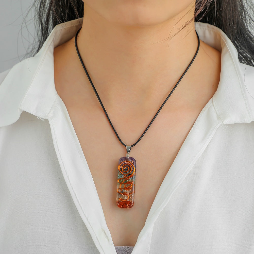 Pendentif 7 Chakras en pierres naturelles et spirale en cuivre, porté par une femme sur une chemise blanche.