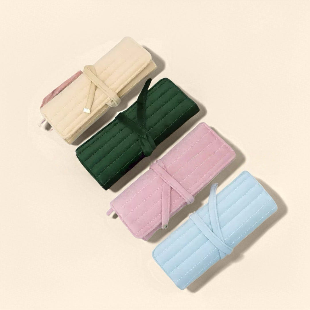 Quatre pochettes à bijoux en velours matelassé de voyage, en couleurs crème, vert forêt, rose poudré et bleu ciel, liées par des rubans.