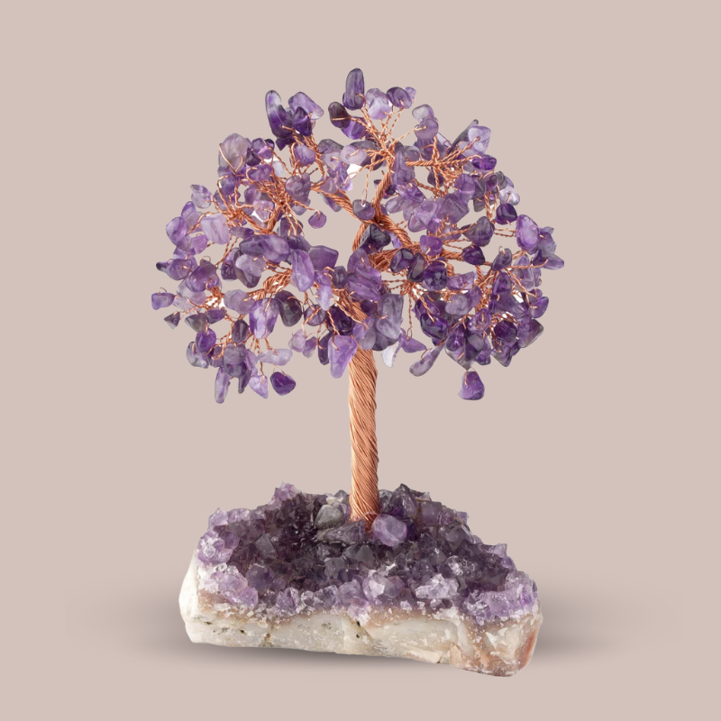 Arbre de vie Trésor en améthyste, avec des feuilles de pierres d'améthyste violettes et un tronc et des branches en fil de cuivre, reposant sur une base d'améthyste brute.