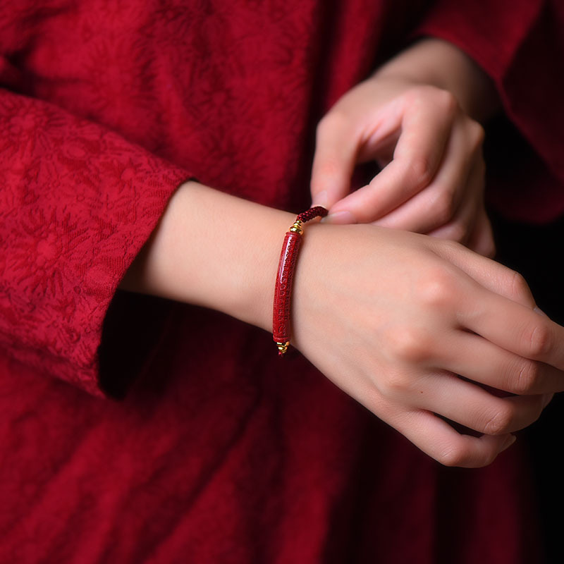 « Élégance asiatique » porté au poignet droit d'une femme qui porte qune robe rouge