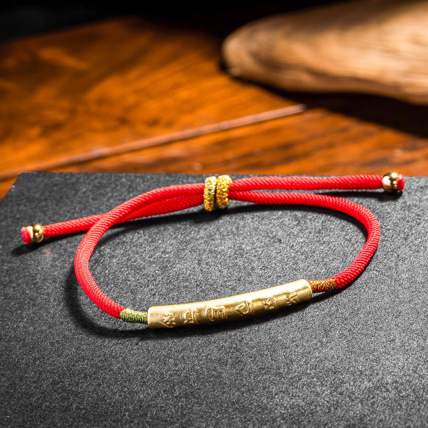 Le bracelet "Mon Bonheur" Six Mantras et Fil Rouge déposé sur une table en bois