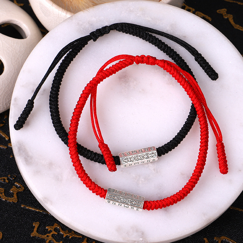 Bracelet "Mantras" en couleur rouge et noire sur un plateau de marbre