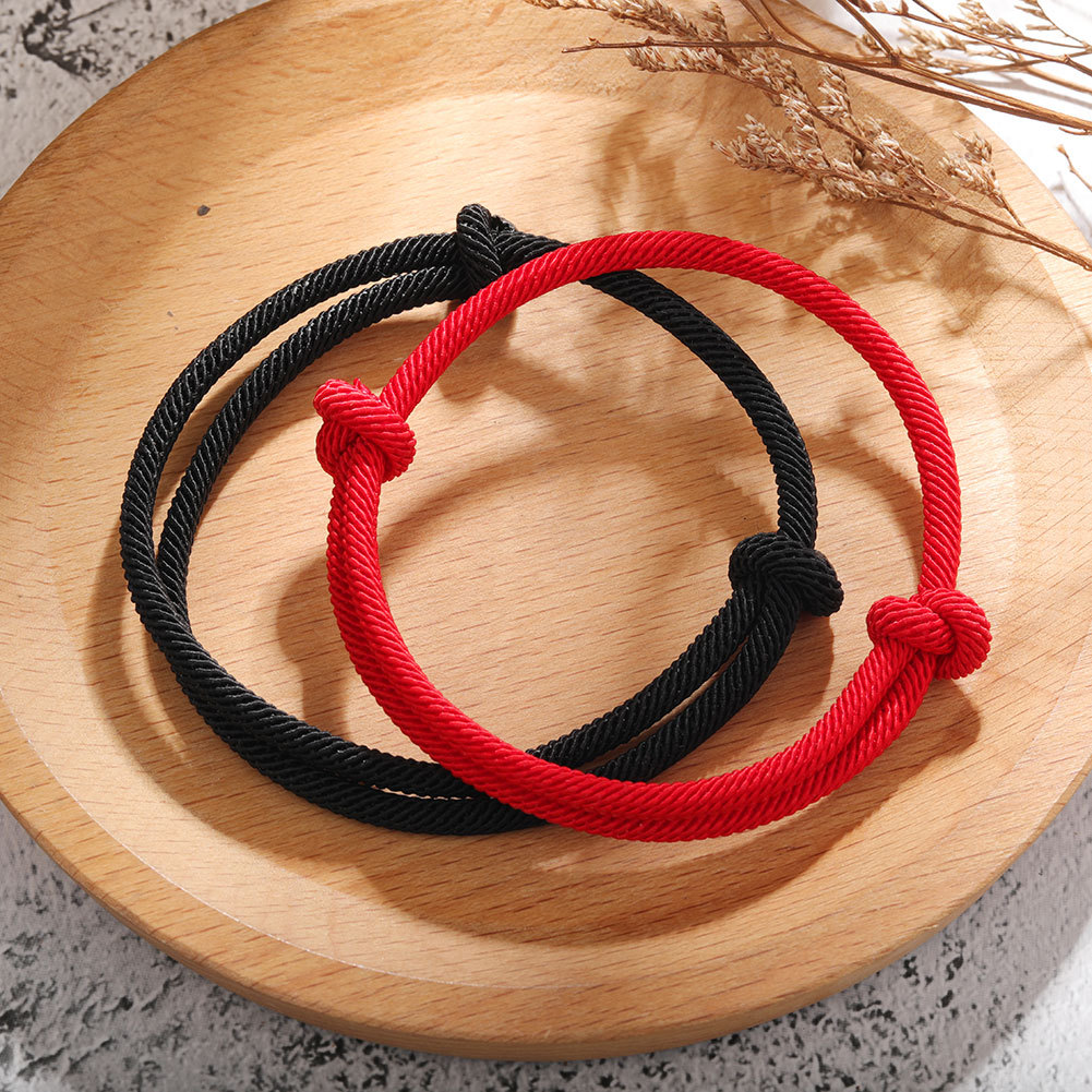 Le bracelet "Force" en rouge et en noir sur un porte bijoux en bois