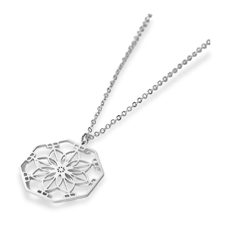 Le collier "Symétrie" en mandala de couler argentée sur fond blanc
